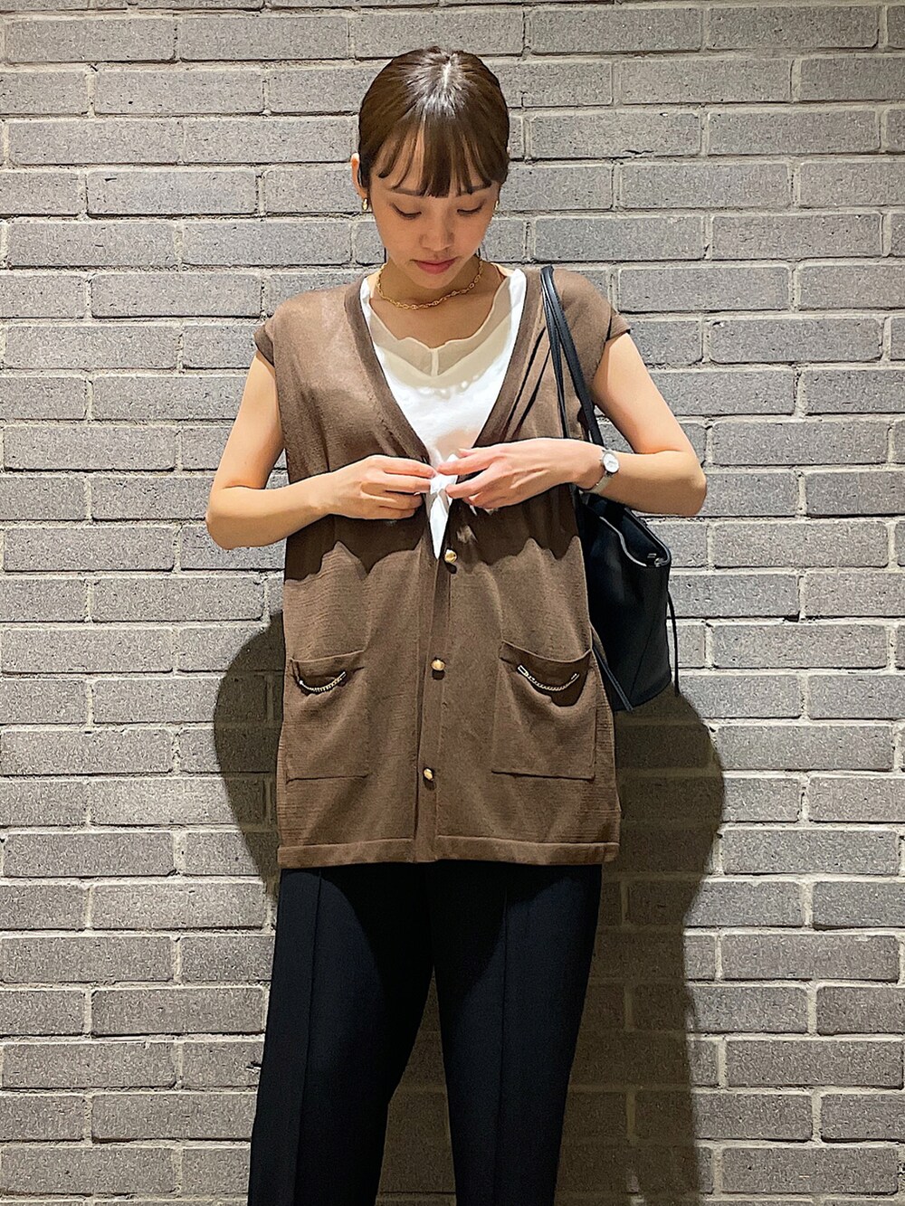 ホワイト系のタンクトップ、グリーン系のベスト、ブラック系のスラックスを着用したレディースの夏コーディネートの5枚目の写真