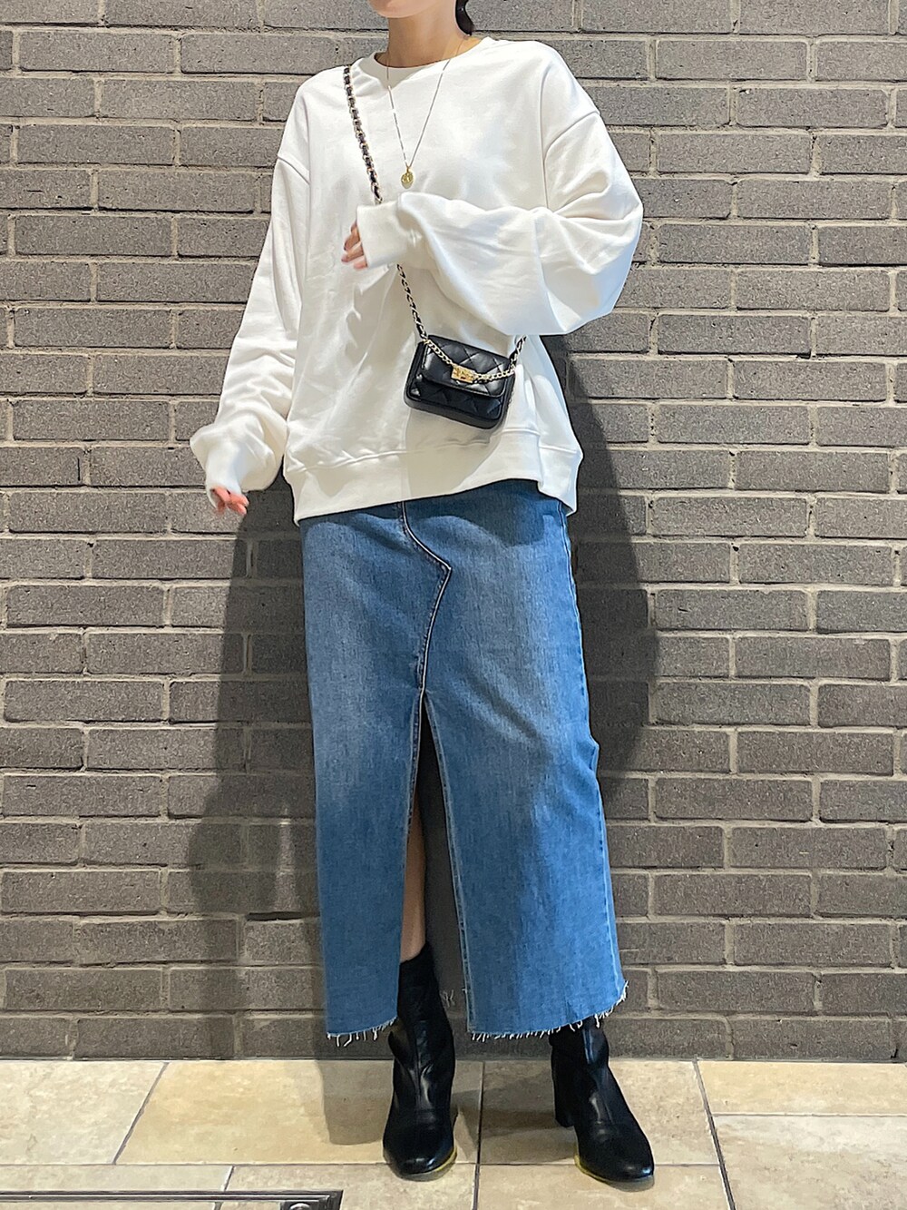 ホワイト系のスウェット、ブラック系のトートバッグ、ブルー系のデニムスカートを着用したレディースの夏コーディネートの5枚目の写真