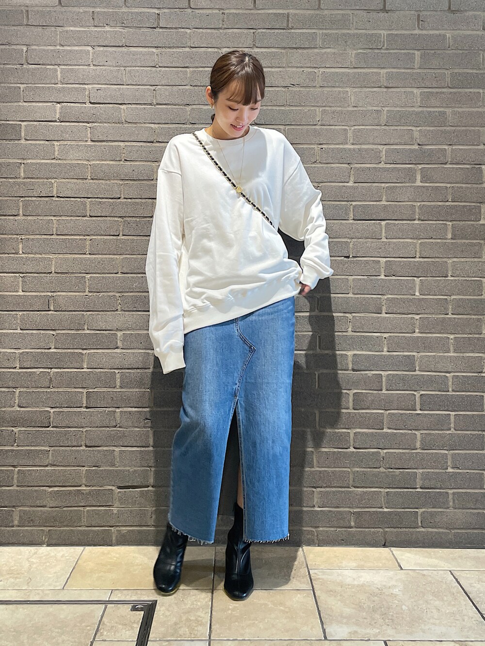 ホワイト系のスウェット、ブラック系のトートバッグ、ブルー系のデニムスカートを着用したレディースの夏コーディネートの4枚目の写真