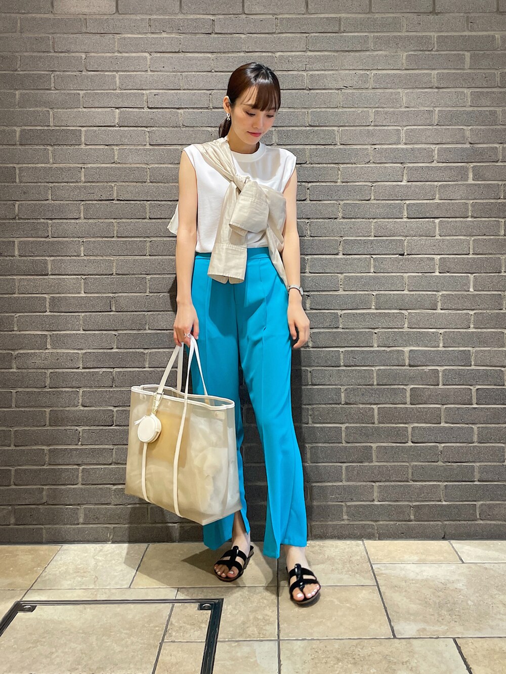ベージュ系のシャツ/ブラウス、ホワイト系のシャツ/ブラウス、ブルー系のスラックスを着用したレディースの夏コーディネートの3枚目の写真