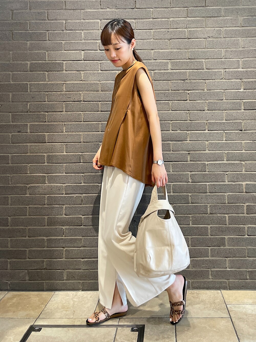 イエロー系のTシャツ/カットソー、ブラック系のトートバッグ、ホワイト系のスラックスを着用したレディースの夏コーディネートの2枚目の写真