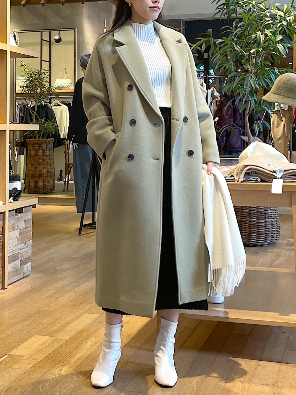 ホワイト系のニット/セーター、グリーン系のチェスターコート、ブラック系のスカートを着用したレディースの冬コーディネートの3枚目の写真