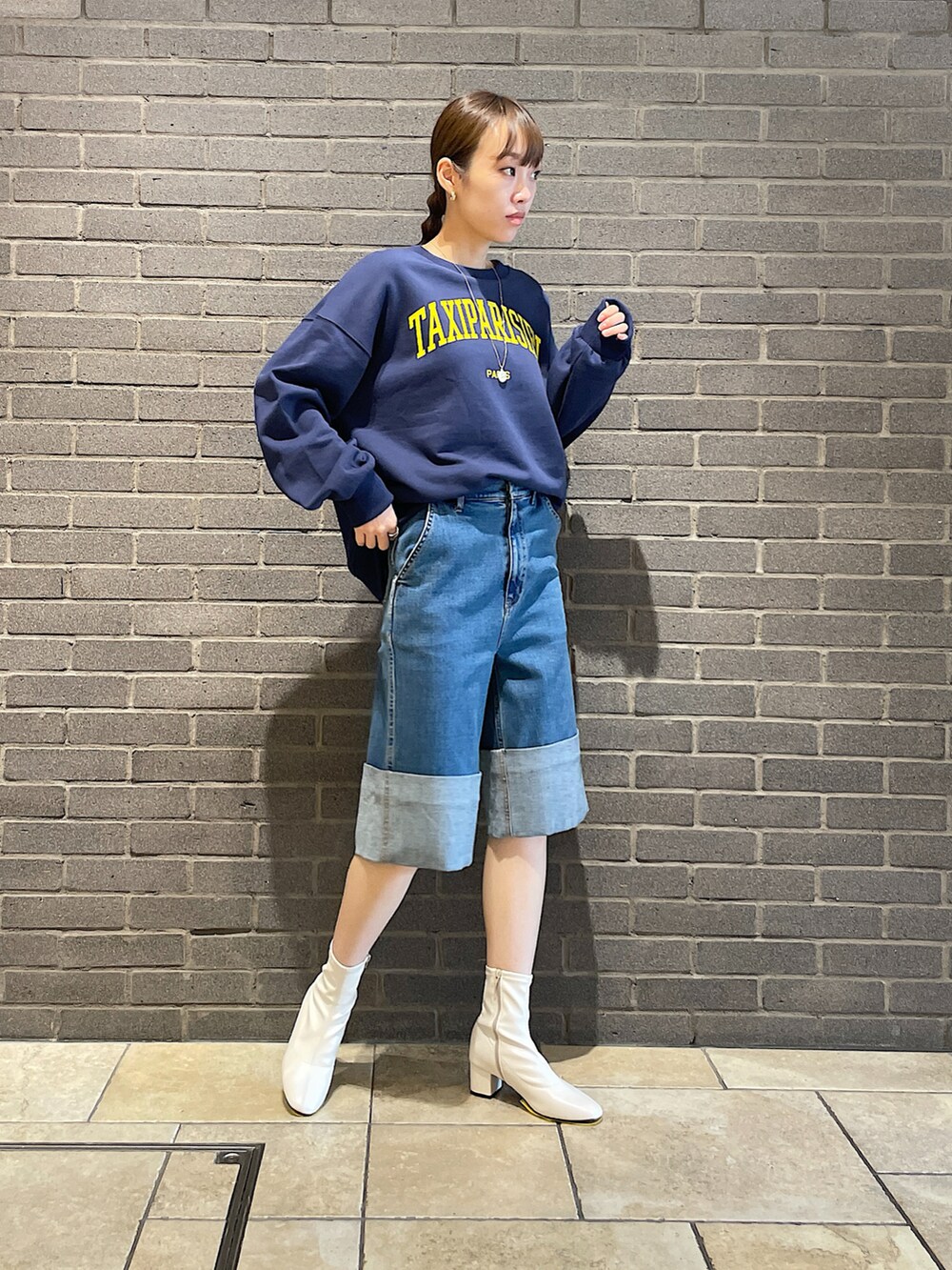 ブルー系のスウェット、ブルー系のデニムパンツ、ホワイト系のブーツを着用したレディースの夏コーディネートの2枚目の写真