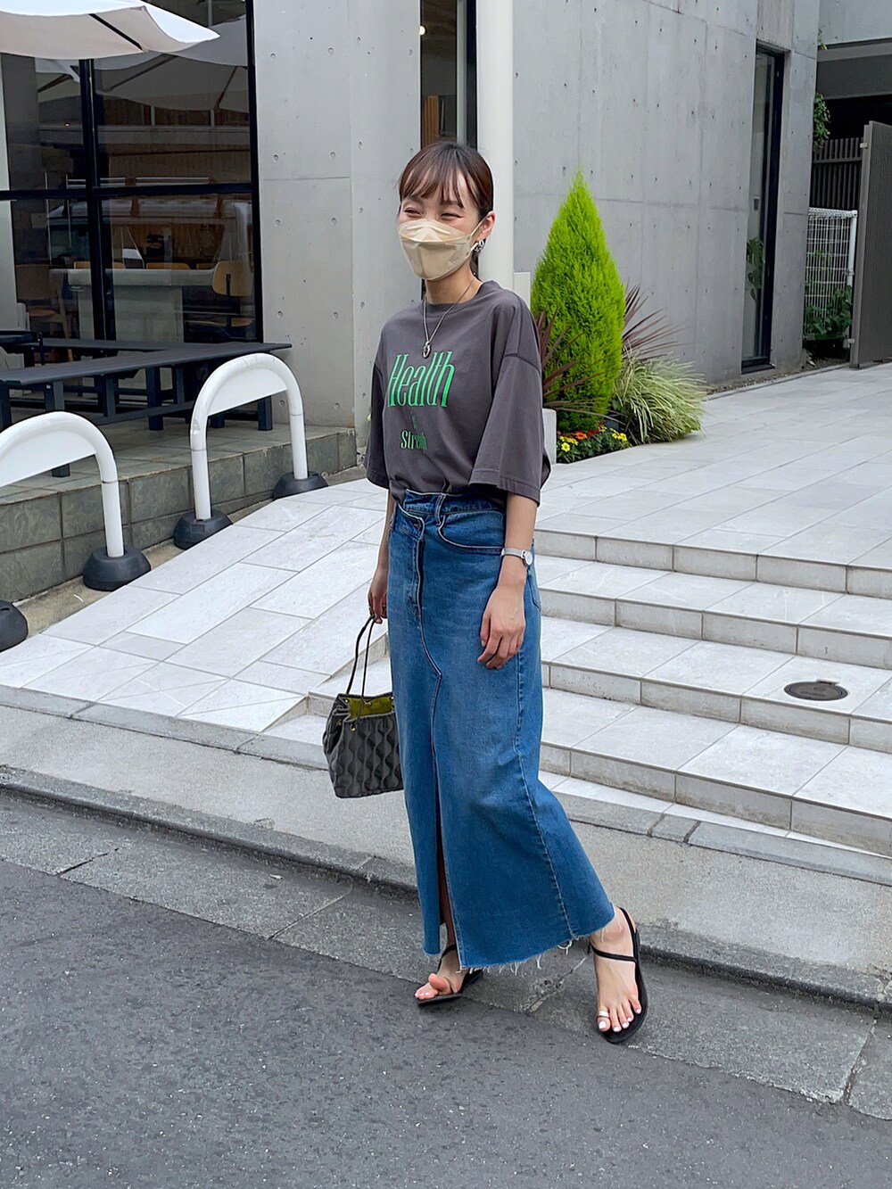 グレー系のTシャツ/カットソー、ブルー系のデニムスカート、グリーン系のショルダーバッグを着用したレディースの夏コーディネートの2枚目の写真