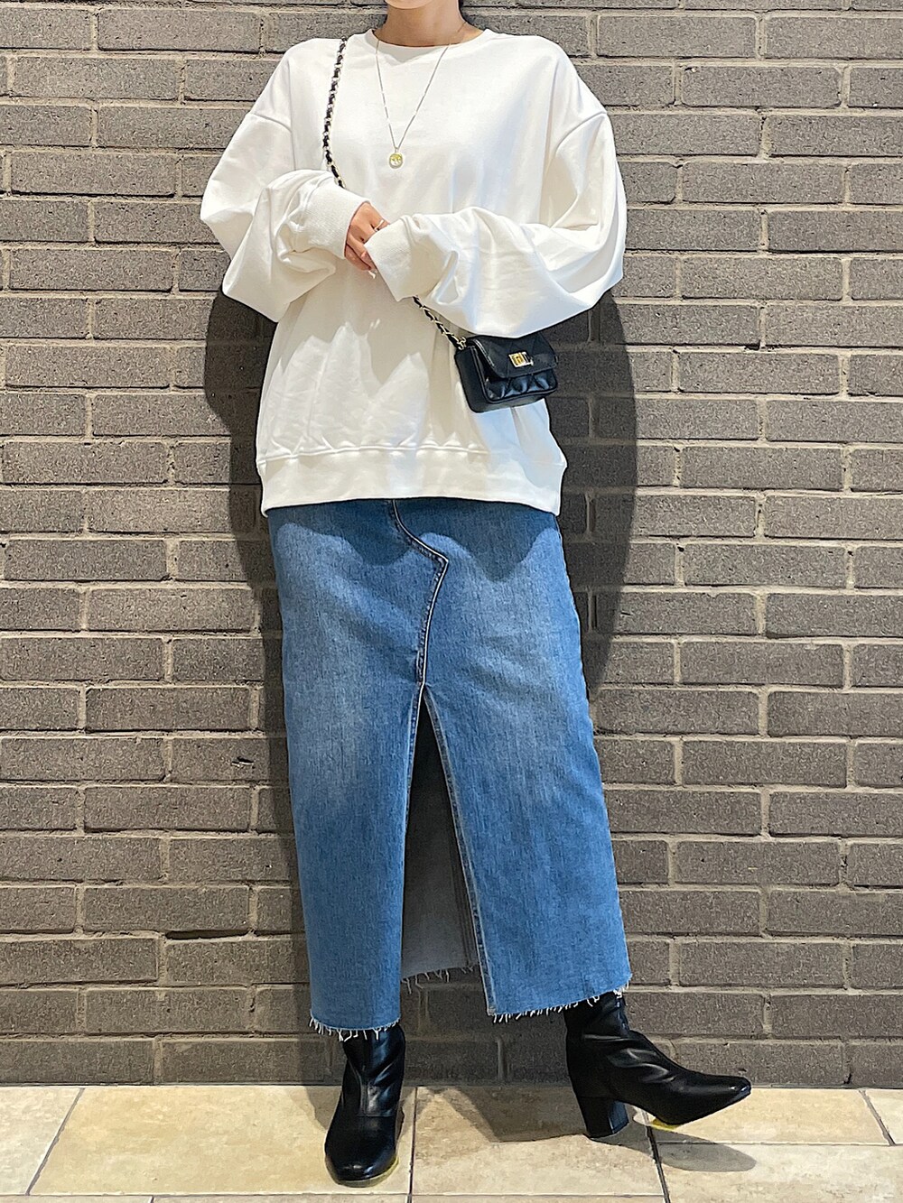 ホワイト系のスウェット、ブラック系のトートバッグ、ブルー系のデニムスカートを着用したレディースの夏コーディネートの3枚目の写真