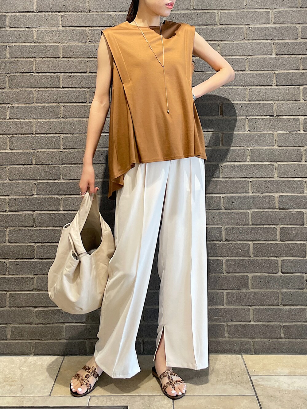 イエロー系のTシャツ/カットソー、ブラック系のトートバッグ、ホワイト系のスラックスを着用したレディースの夏コーディネートの4枚目の写真