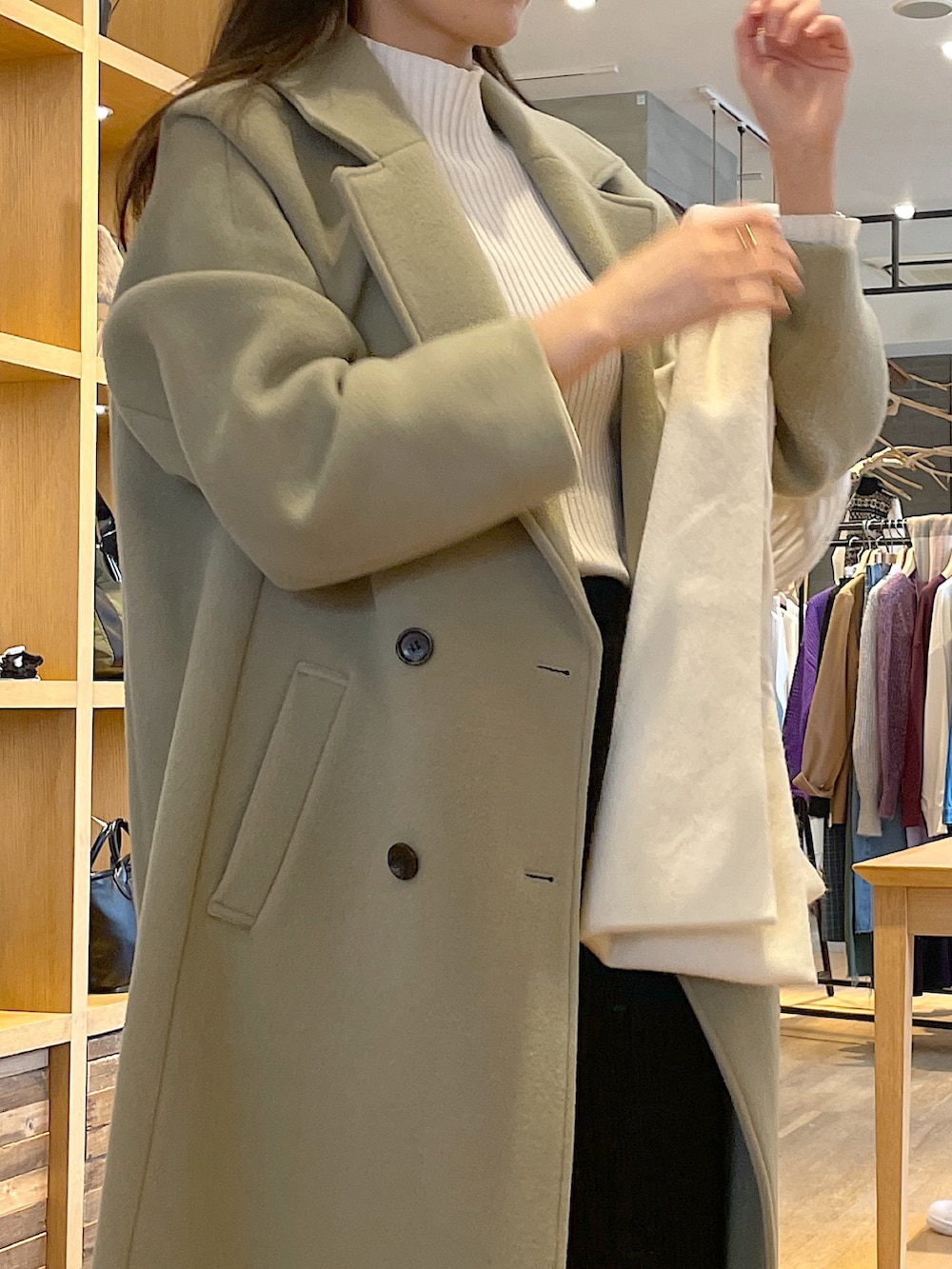 ホワイト系のニット/セーター、グリーン系のチェスターコート、ブラック系のスカートを着用したレディースの冬コーディネートの4枚目の写真