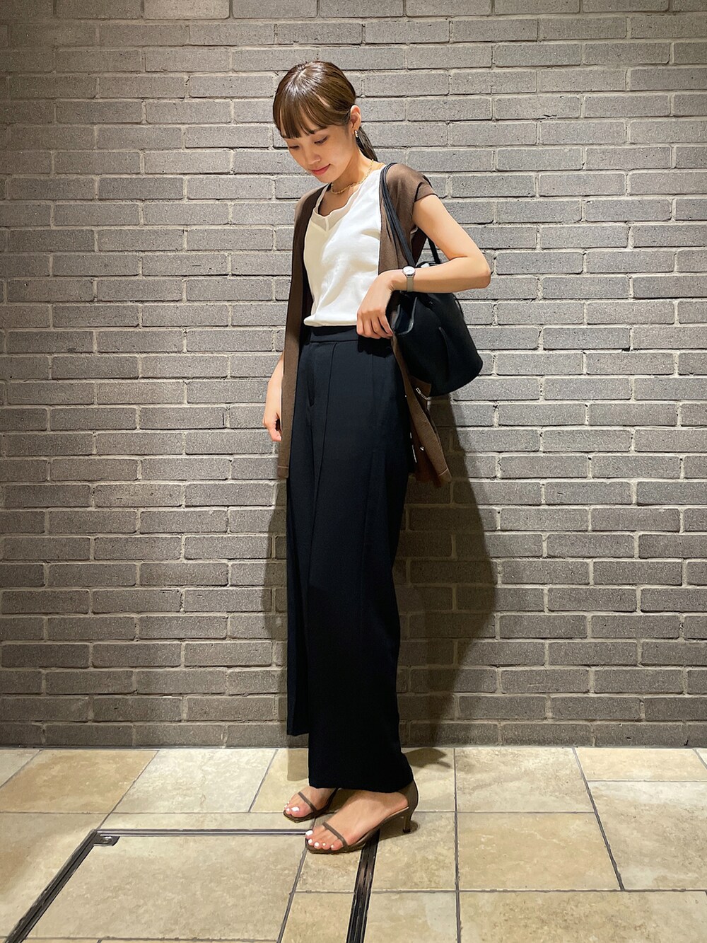 ホワイト系のタンクトップ、グリーン系のベスト、ブラック系のスラックスを着用したレディースの夏コーディネートの2枚目の写真