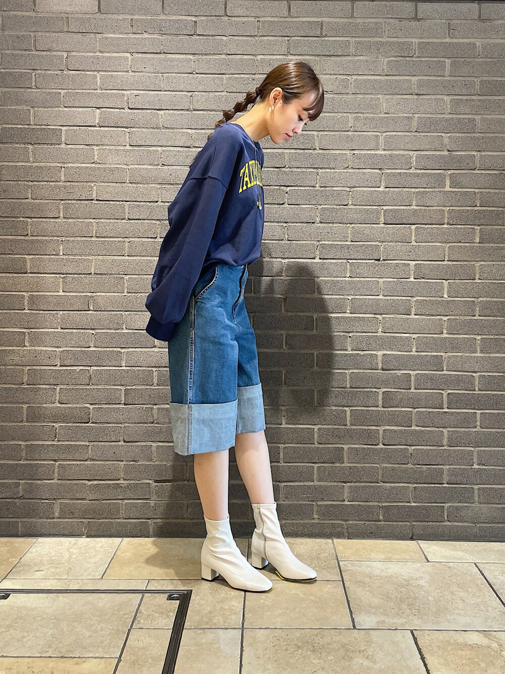 ブルー系のスウェット、ブルー系のデニムパンツ、ホワイト系のブーツを着用したレディースの夏コーディネートの3枚目の写真