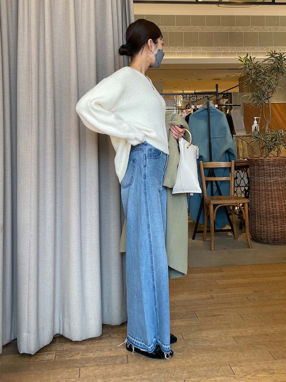 ホワイト系のトートバッグ、ブルー系のデニムパンツ、グリーン系のチェスターコートを着用したレディースの冬コーディネートの5枚目の写真