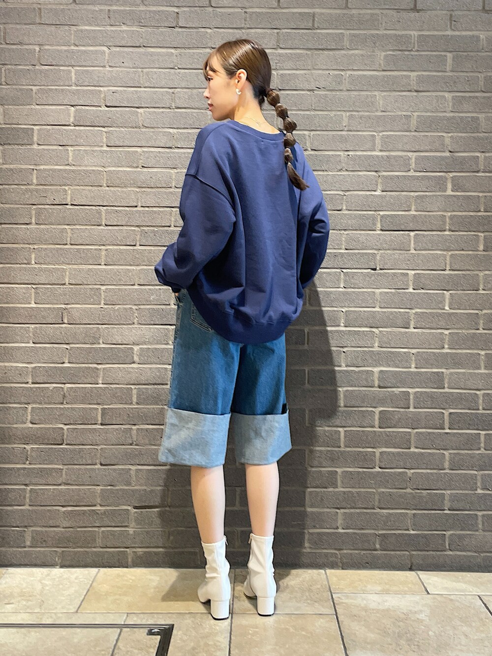 ブルー系のスウェット、ブルー系のデニムパンツ、ホワイト系のブーツを着用したレディースの夏コーディネートの4枚目の写真