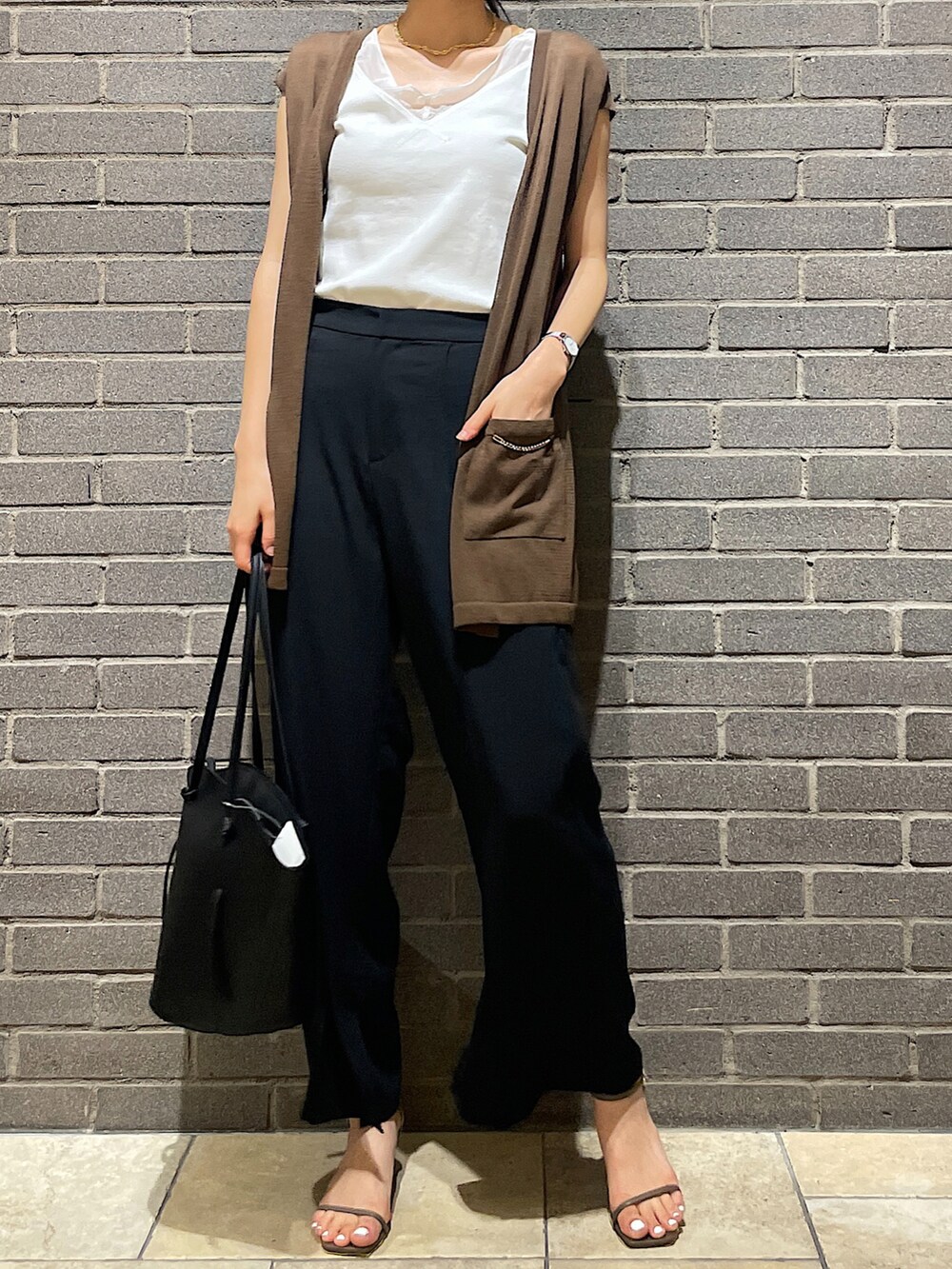 ホワイト系のタンクトップ、グリーン系のベスト、ブラック系のスラックスを着用したレディースの夏コーディネートの3枚目の写真