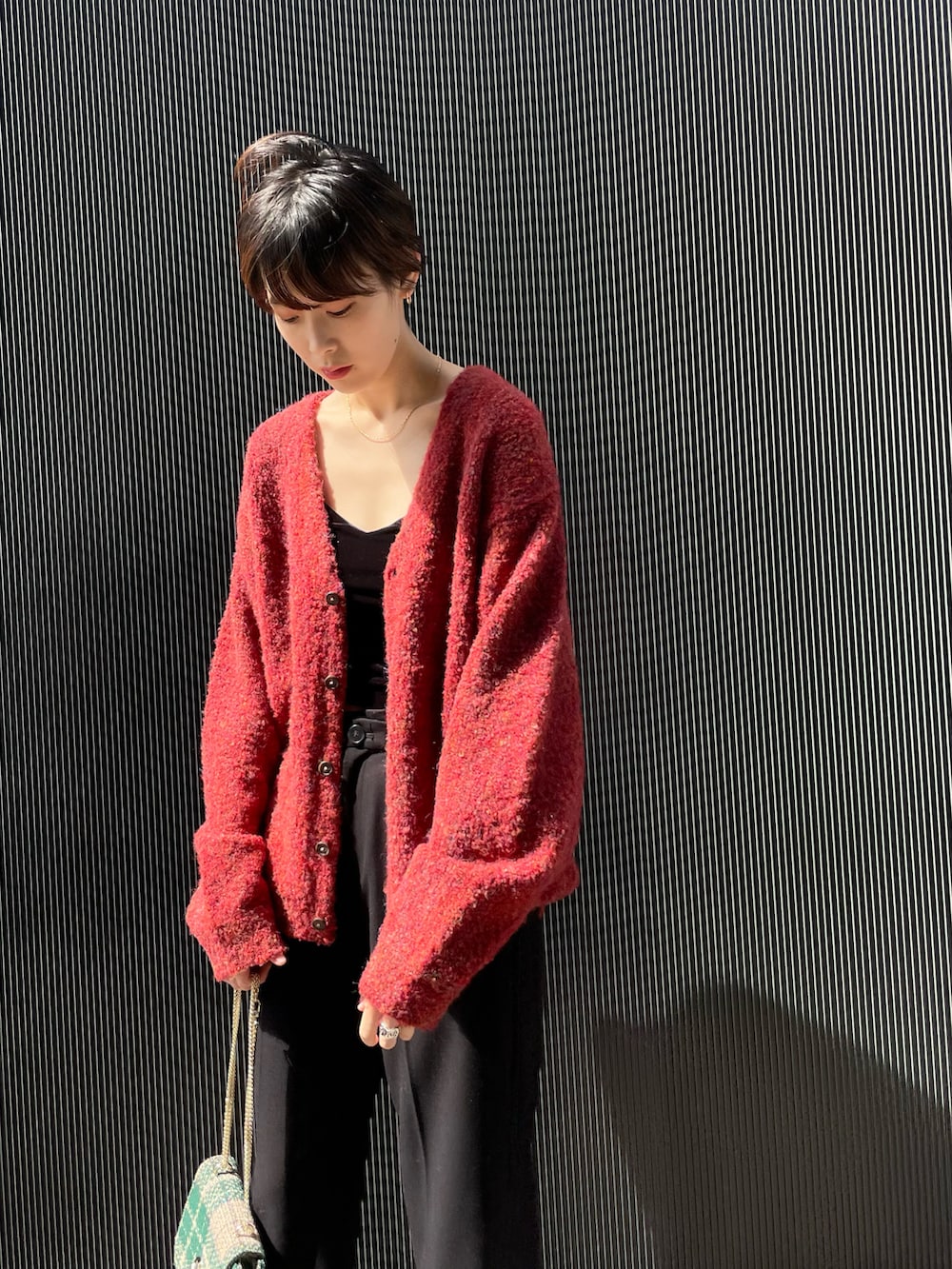 レッド系のカーディガン/ボレロ、ブラック系のキャミソール、ブラック系のその他パンツを着用したレディースの秋コーディネートの2枚目の写真