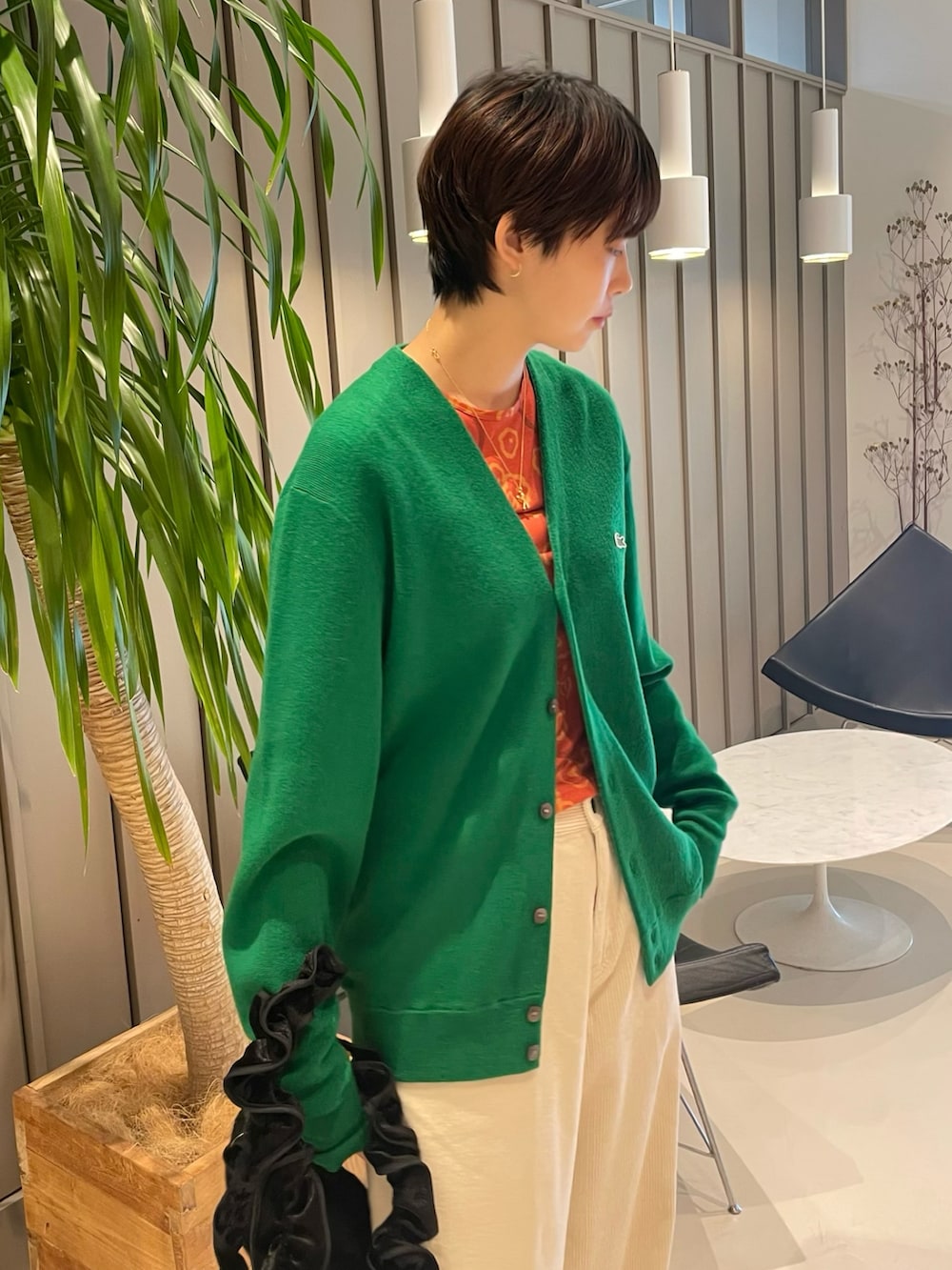 オレンジ系のTシャツ/カットソー、ブラック系のトートバッグ、グリーン系のカーディガン/ボレロを着用したレディースの夏コーディネートの3枚目の写真