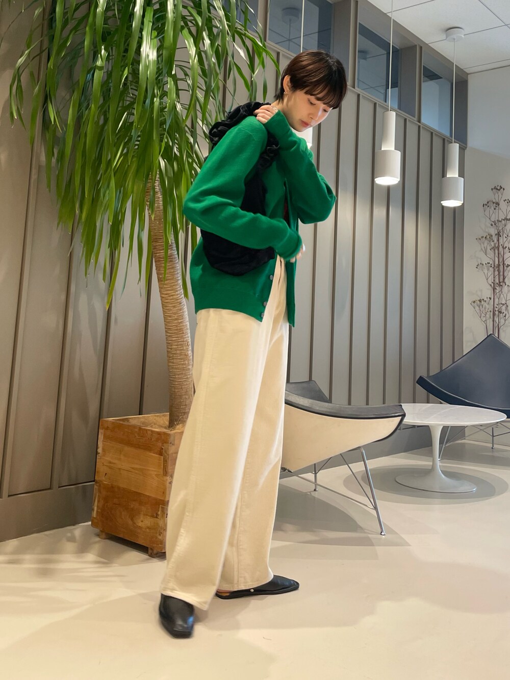 オレンジ系のTシャツ/カットソー、ブラック系のトートバッグ、グリーン系のカーディガン/ボレロを着用したレディースの夏コーディネートの2枚目の写真