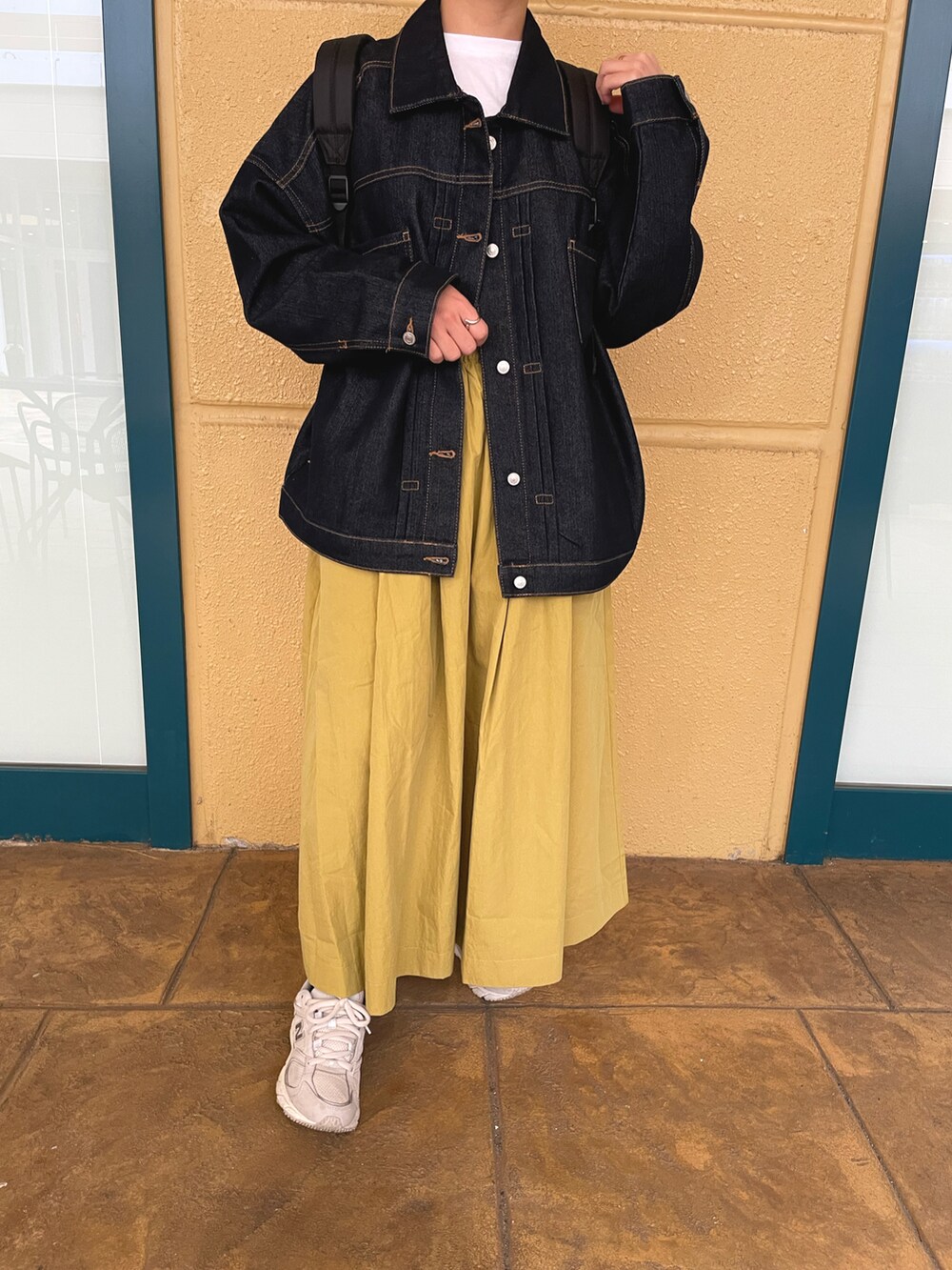 イエロー系のスカート、ホワイト系のTシャツ/カットソー、ブルー系のデニムジャケットを着用したレディースの春コーディネートの3枚目の写真
