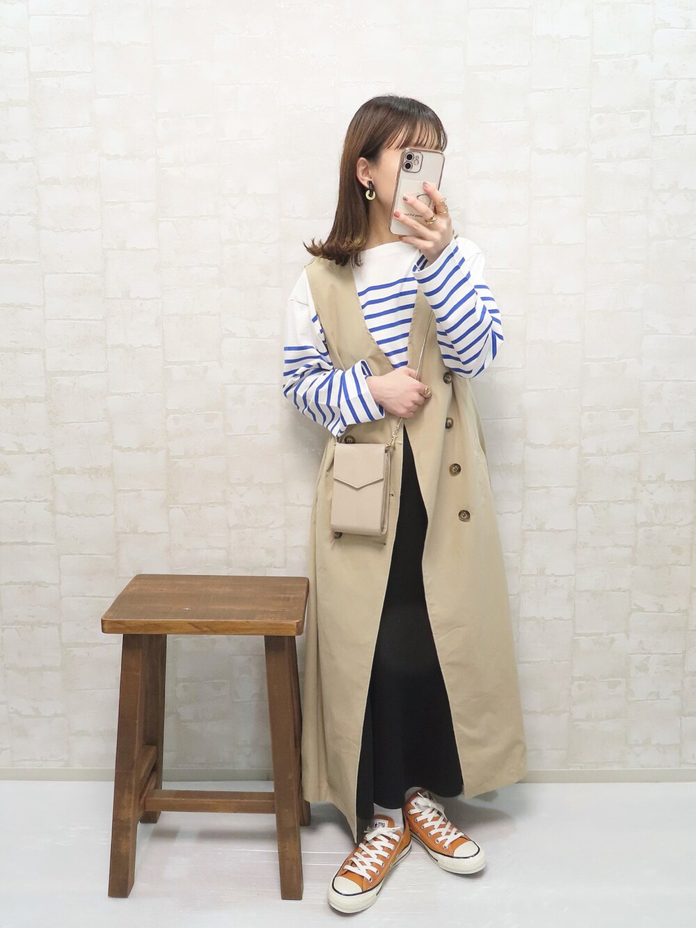 ベージュ系のトレンチコート、ブルー系のTシャツ/カットソー、ブラック系のスカートを着用したレディースの春コーディネートの3枚目の写真