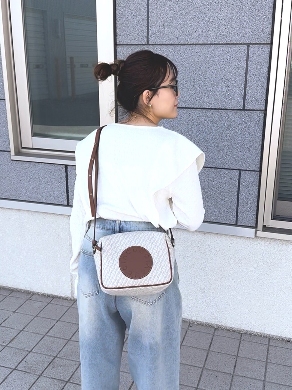 ホワイト系のTシャツ/カットソー、ブルー系のデニムパンツ、ホワイト系のショルダーバッグを着用したレディースの冬コーディネートの3枚目の写真