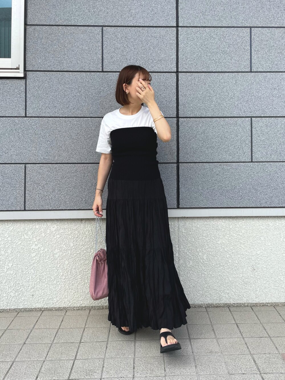 ブラック系のチューブトップ、ブラック系のスカート、ピンク系のショルダーバッグを着用したレディースの夏コーディネートの5枚目の写真