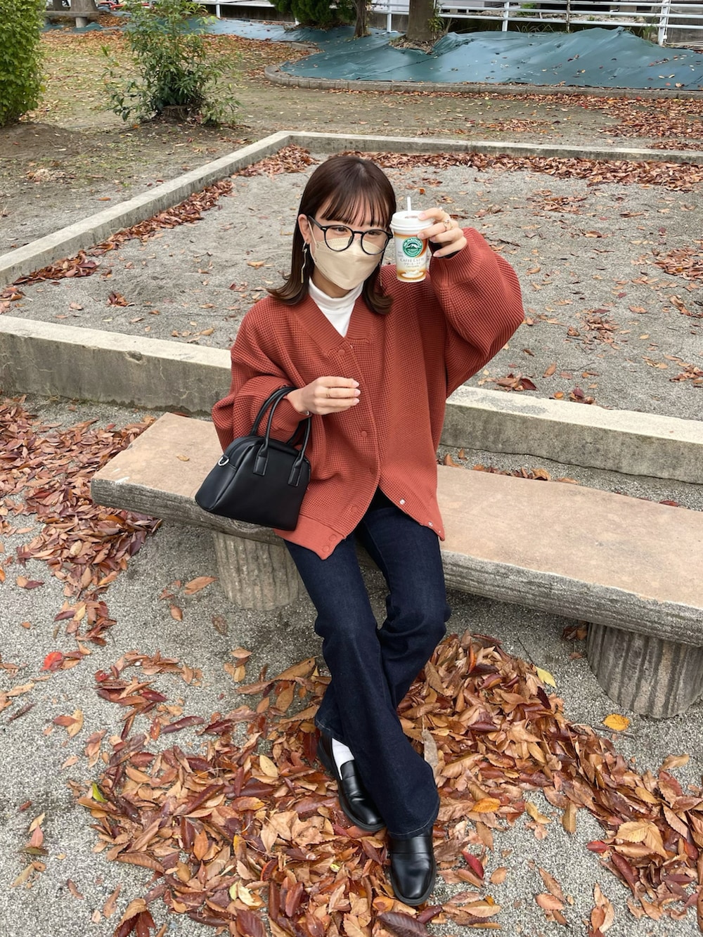 レッド系のカーディガン/ボレロ、ブルー系のデニムパンツ、ブラック系のボストンバッグを着用したレディースの秋コーディネートの5枚目の写真