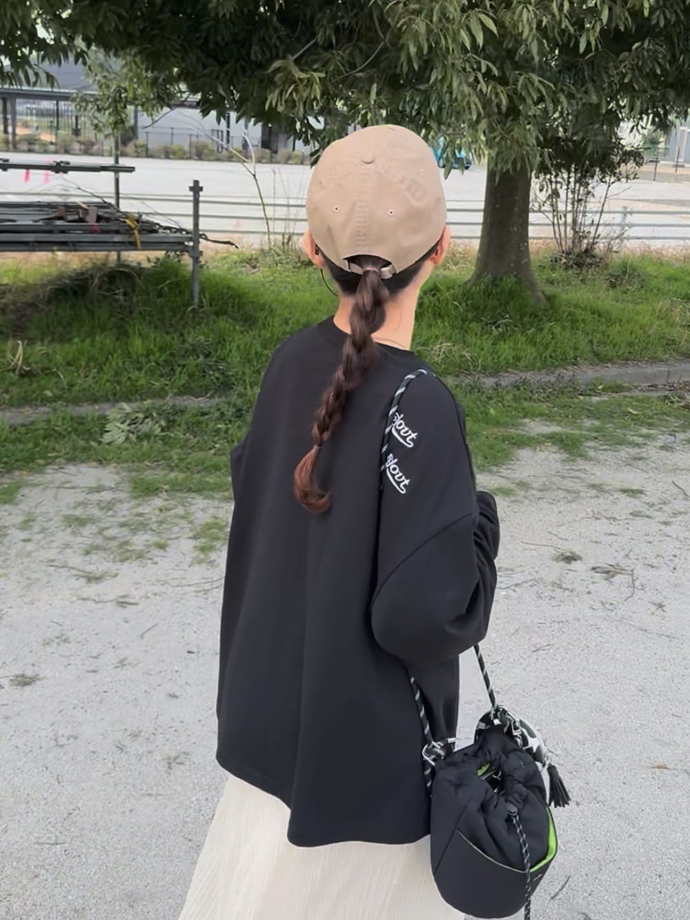 ブラック系のTシャツ/カットソー、ホワイト系のスカート、ブラック系のバッグを着用したレディースの春コーディネートの4枚目の写真