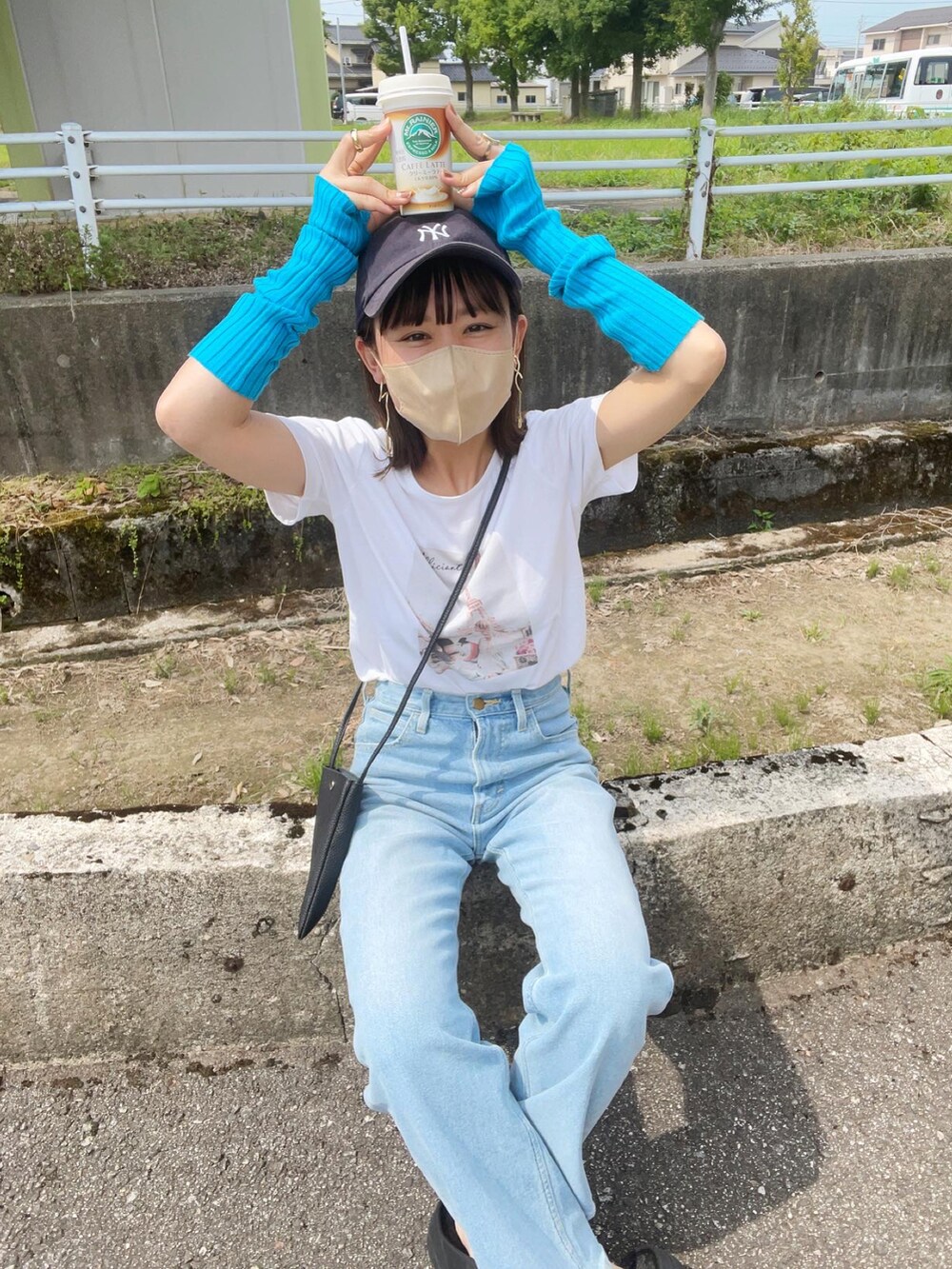 ブルー系のデニムパンツ、ホワイト系のTシャツ/カットソー、ブラック系のショルダーバッグを着用したレディースの夏コーディネートの4枚目の写真