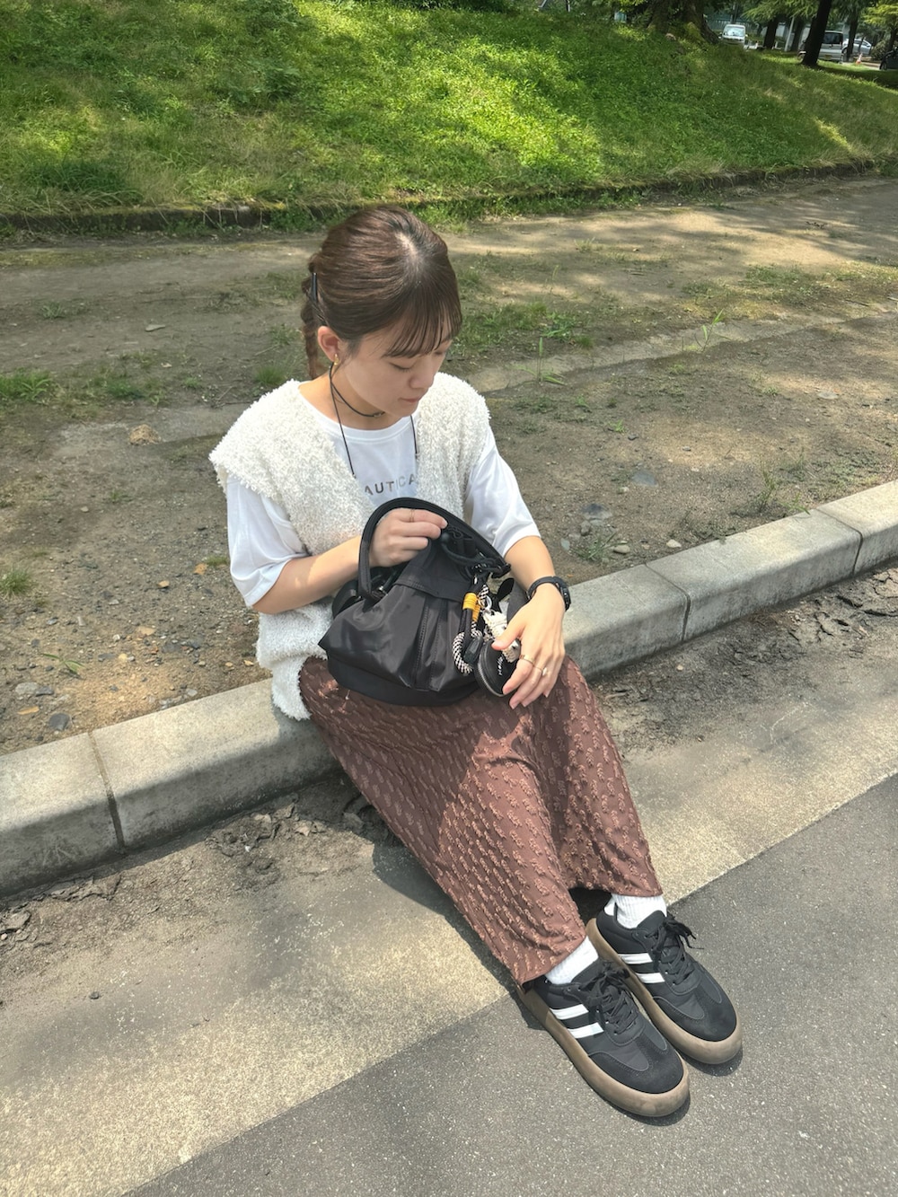 ブラウン系のスカート、ホワイト系のトップス、ブラック系のバッグを着用したレディースの夏コーディネートの5枚目の写真