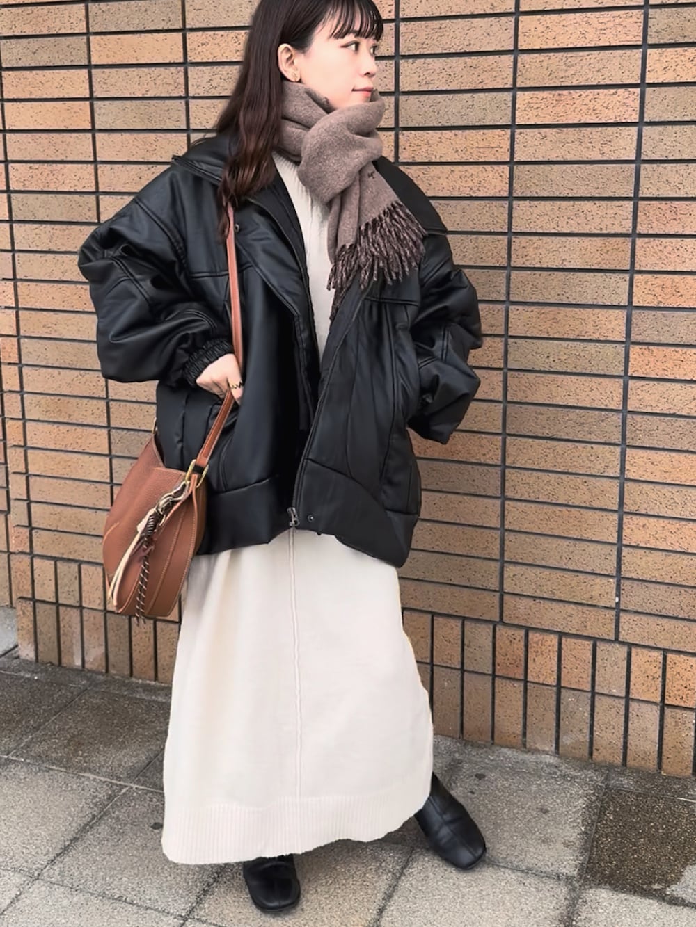 ブラック系のブルゾン、ホワイト系のワンピース、ブラウン系のショルダーバッグを着用したレディースの冬コーディネートの4枚目の写真