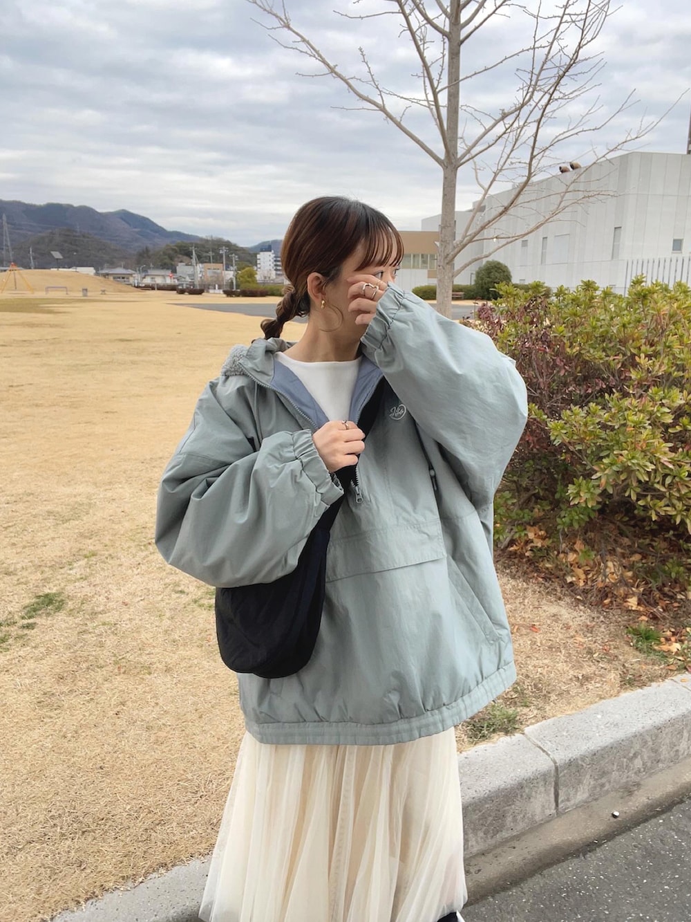 ブルー系のブルゾン、ホワイト系のスカート、ブラック系のショルダーバッグを着用したレディースの冬コーディネートの4枚目の写真