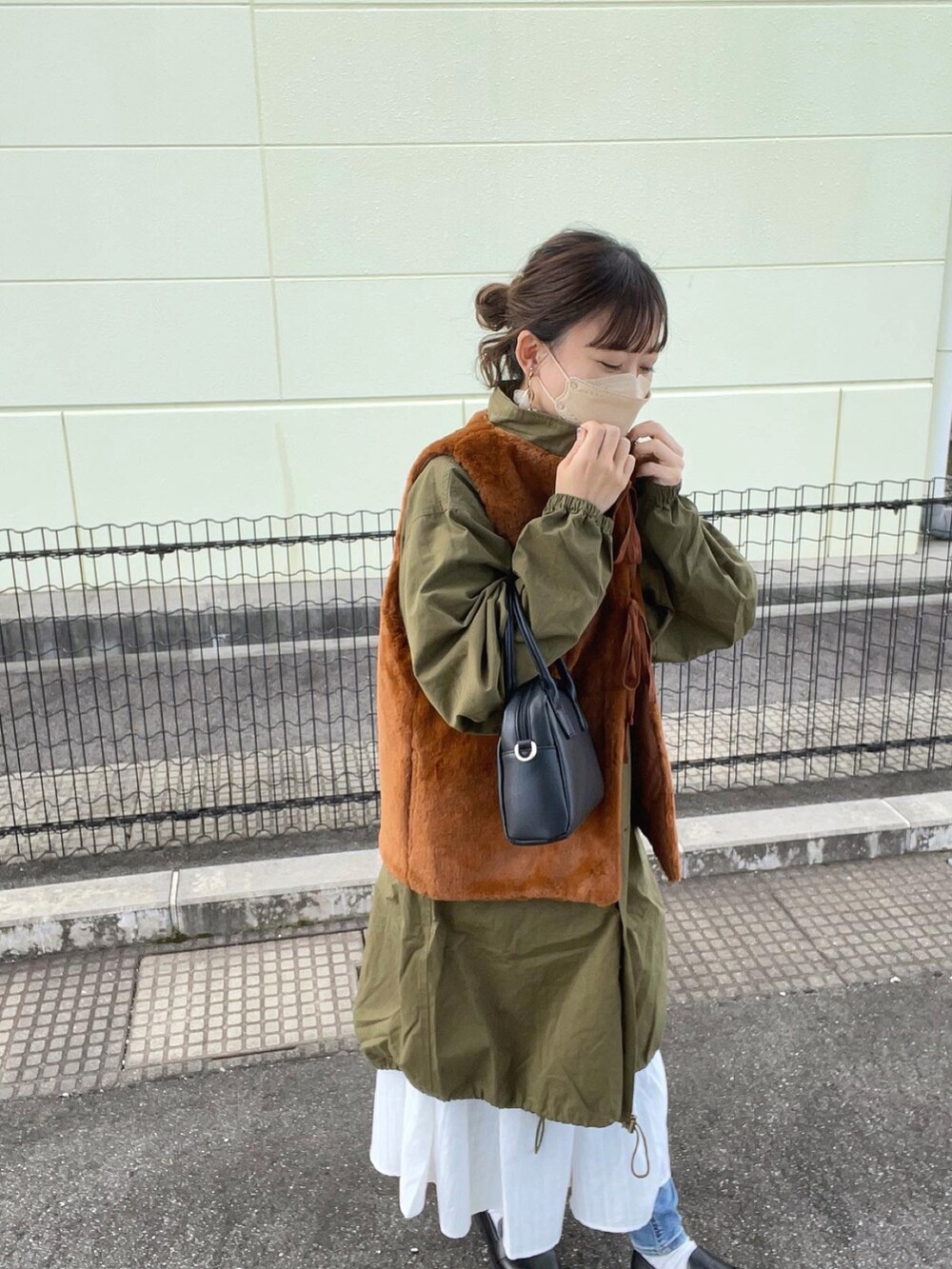 グリーン系のモッズコート、ホワイト系のシャツワンピース、ブラック系のボストンバッグを着用したレディースの秋コーディネートの5枚目の写真