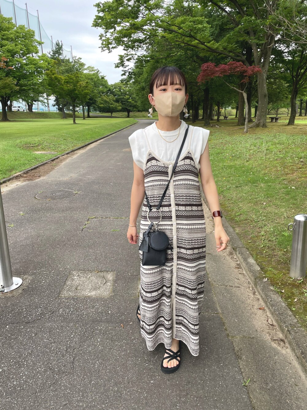 ベージュ系のワンピース、ホワイト系のニット/セーター、ブラック系のショルダーバッグを着用したレディースの夏コーディネートの5枚目の写真