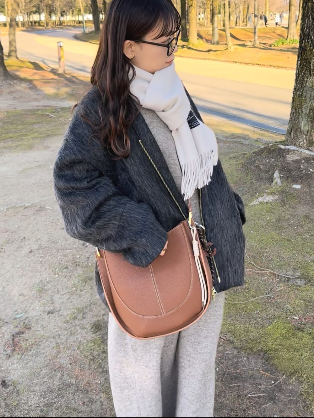 ブラック系のノーカラーコート、ベージュ系のワンピース、ブラック系のシューズを着用したレディースの冬コーディネートの2枚目の写真