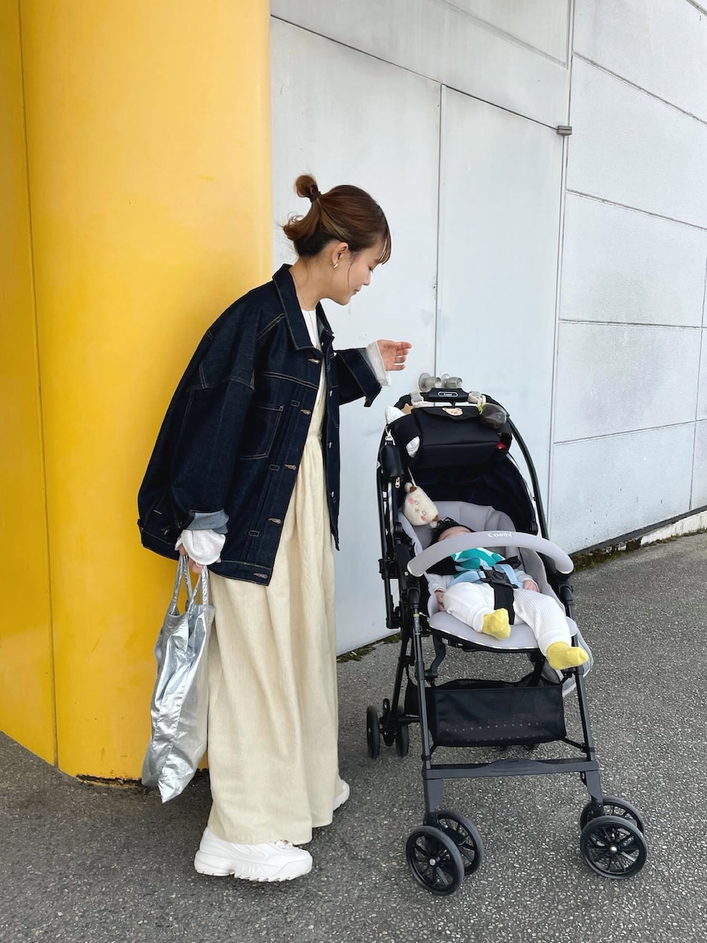 イエロー系のワンピース、ブルー系のデニムジャケット、シルバー系のトートバッグを着用したレディースの春コーディネートの4枚目の写真