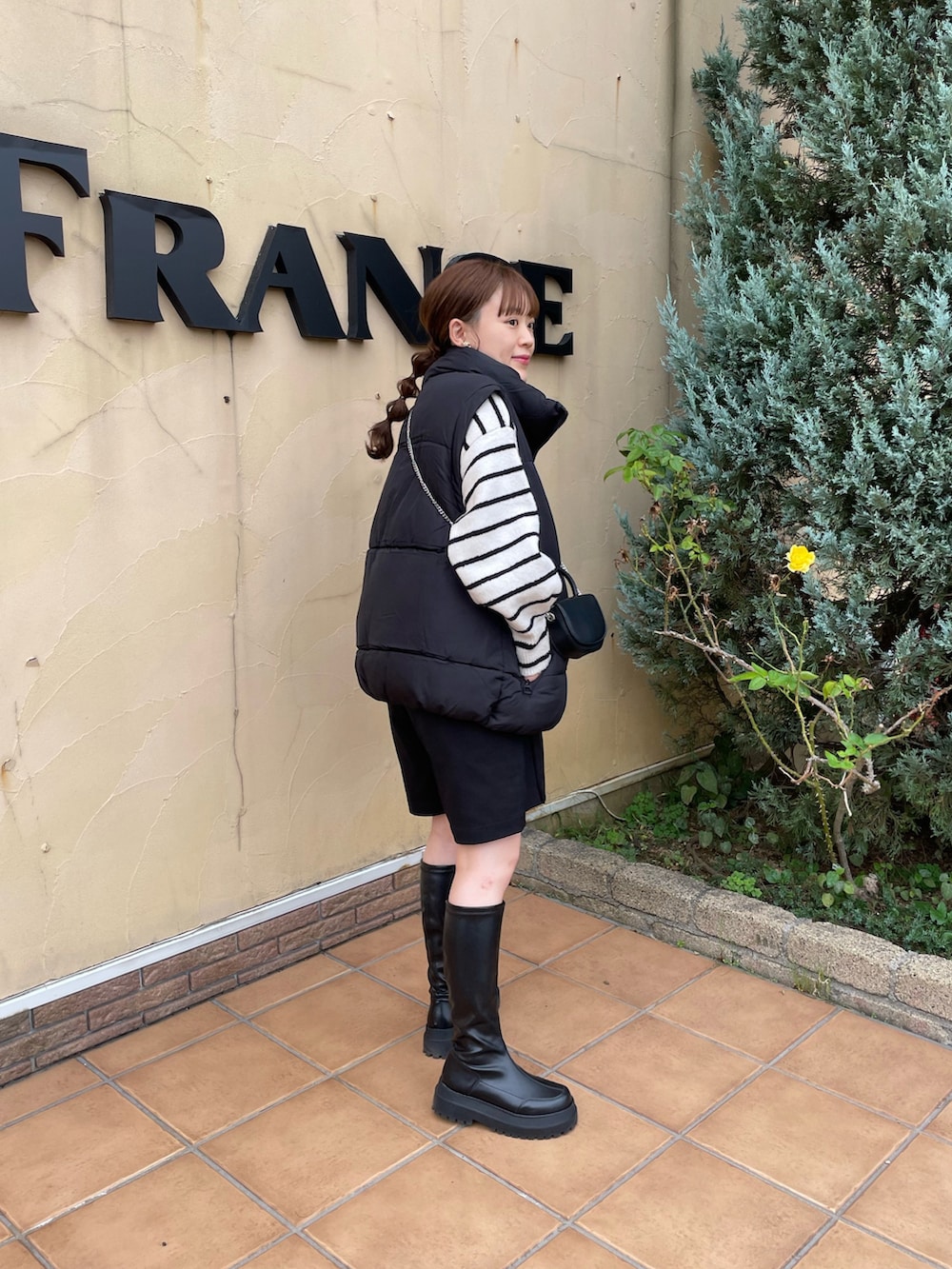 ブラック系のベスト、ブラック系のショルダーバッグ、ホワイト系のニット/セーターを着用したレディースの秋コーディネートの2枚目の写真