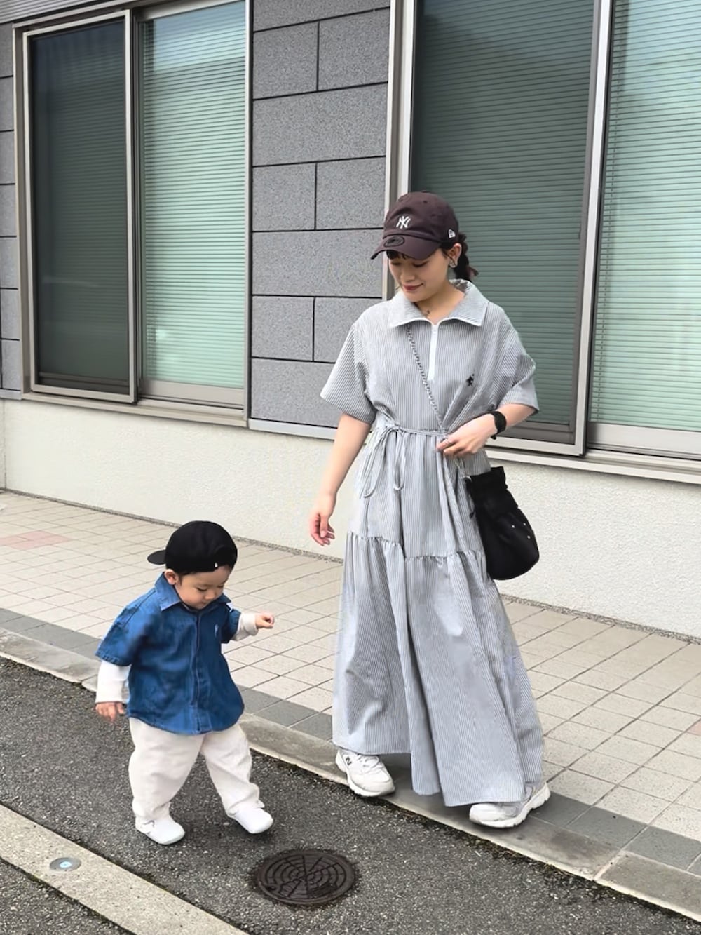 ブラック系のワンピース、ホワイト系のスニーカー、ブラック系のショルダーバッグを着用したレディースの夏コーディネートの4枚目の写真