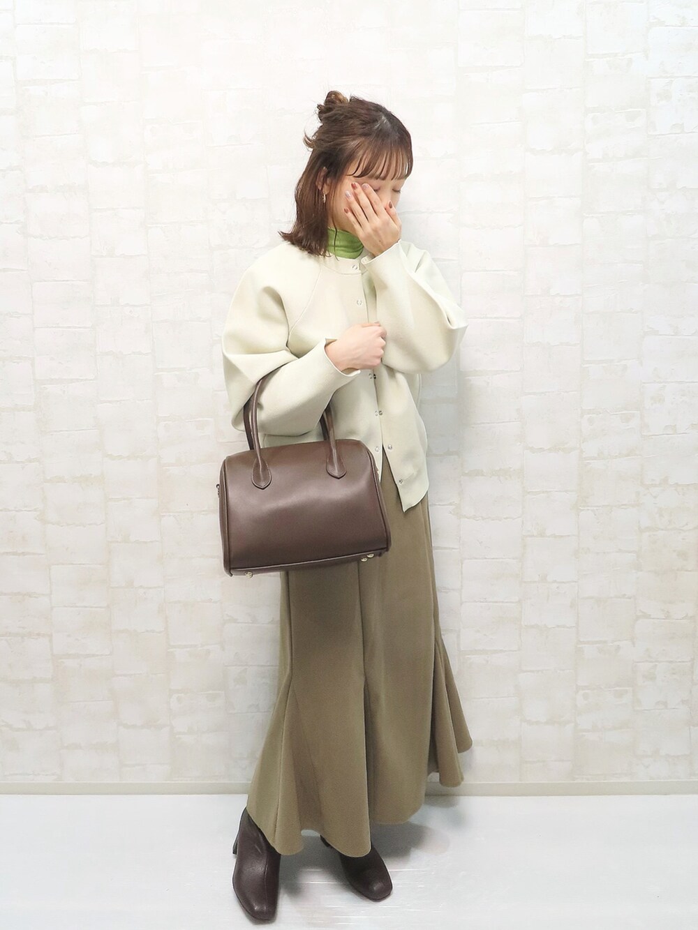 ベージュ系のニット/セーター、グリーン系のニット/セーター、ブラック系のデニムパンツを着用したレディースの冬コーディネートの2枚目の写真