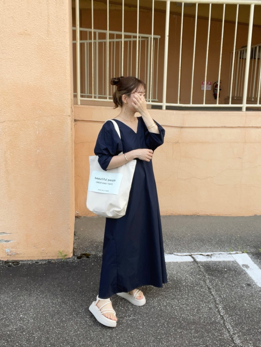 ブルー系のワンピース、ホワイト系のトートバッグ、ホワイト系のサンダルを着用したレディースの夏コーディネートの3枚目の写真