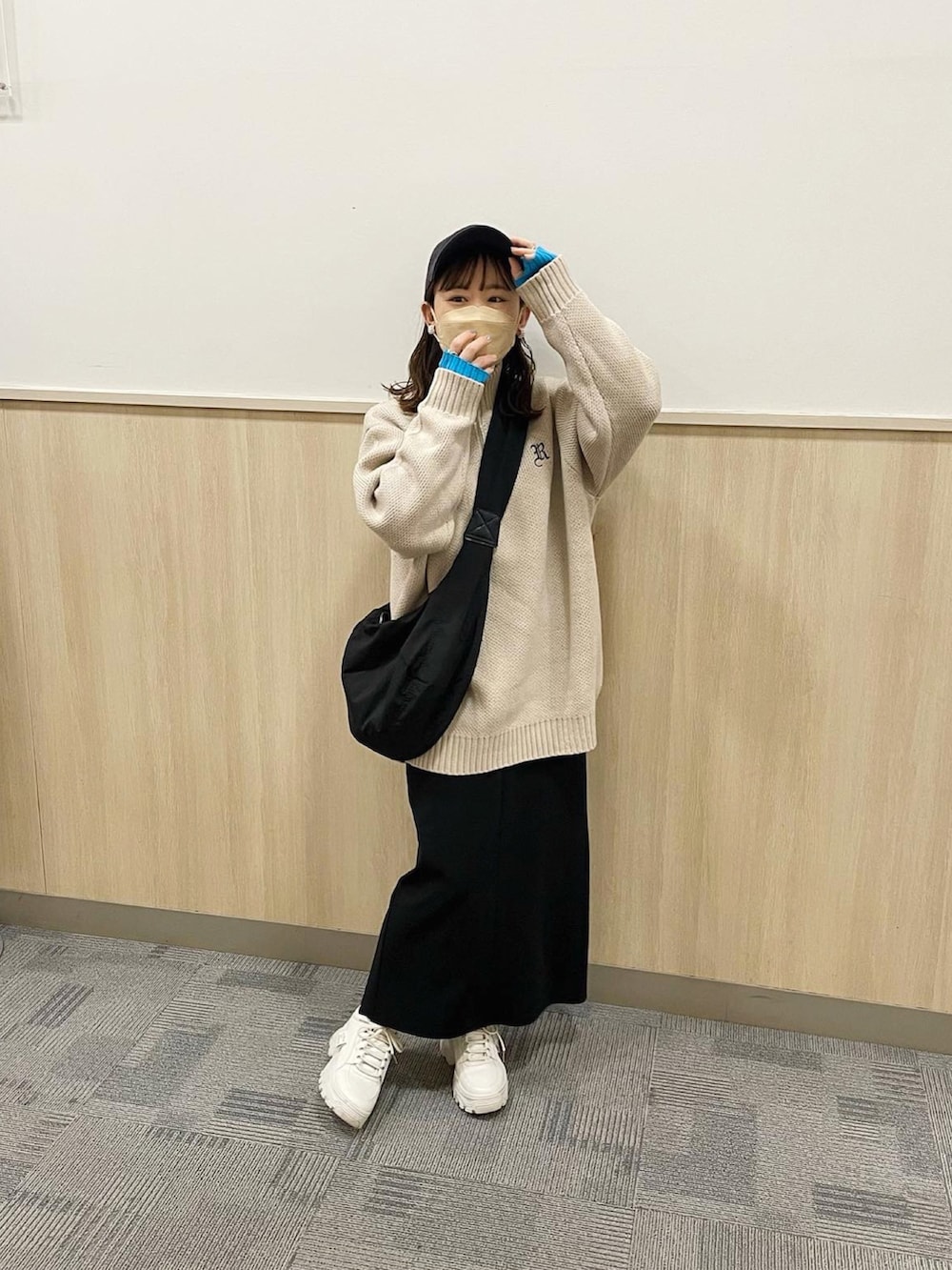 ベージュ系のニット/セーター、ブラック系のスカート、ブラック系のショルダーバッグを着用したレディースの春コーディネートの4枚目の写真