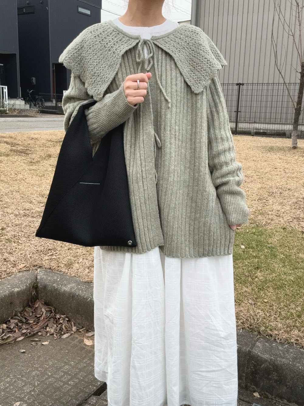 ブラック系のトートバッグ、ホワイト系のスニーカー、グリーン系のカーディガン/ボレロを着用したレディースの冬コーディネートの3枚目の写真