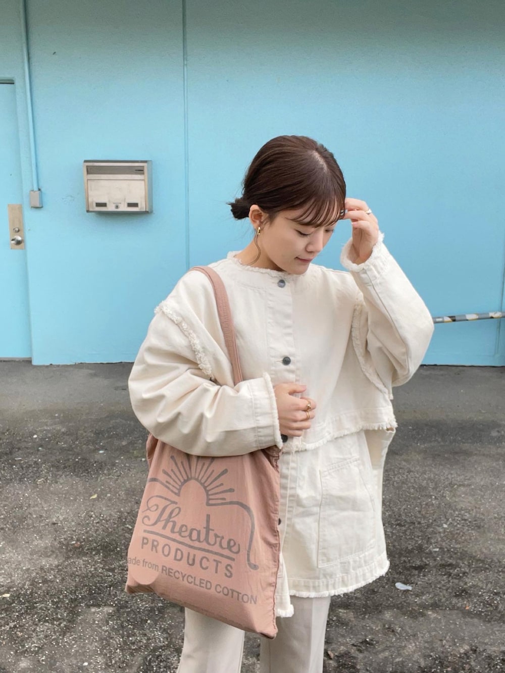 ピンク系のトートバッグ、ホワイト系のデニムジャケット、ホワイト系のスラックスを着用したレディースの春コーディネートの2枚目の写真