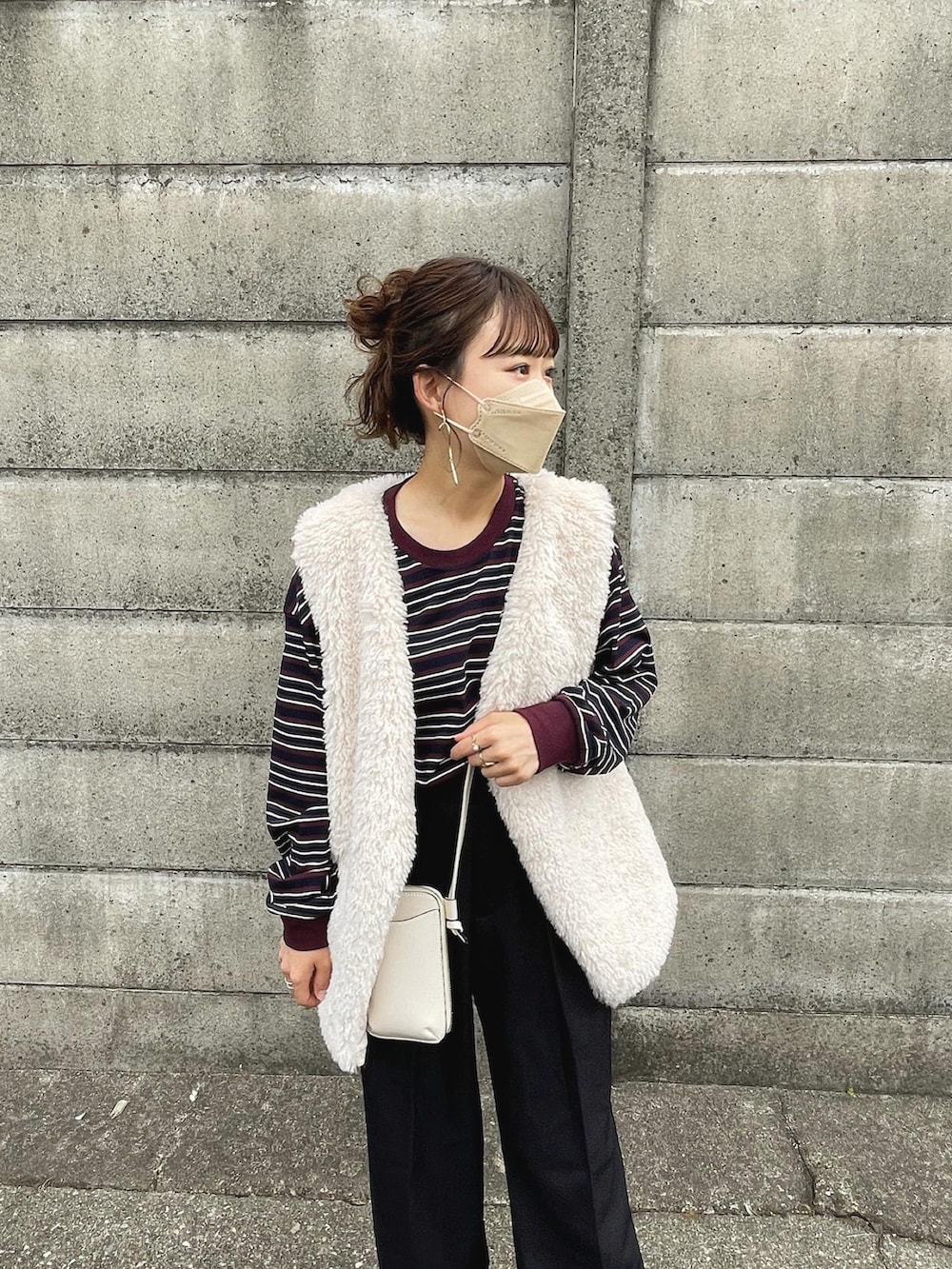 レッド系のトップス、ブラック系のパンツ、グレー系のベストを着用したレディースの秋コーディネートの2枚目の写真