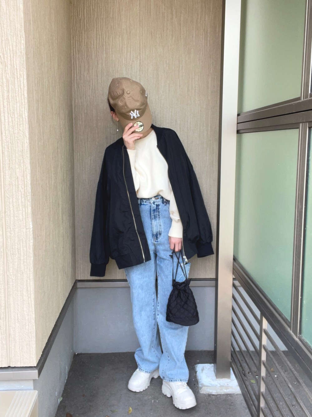 ブラック系のブルゾン、ホワイト系のニット/セーター、その他のデニムパンツを着用したレディースの春コーディネートの2枚目の写真