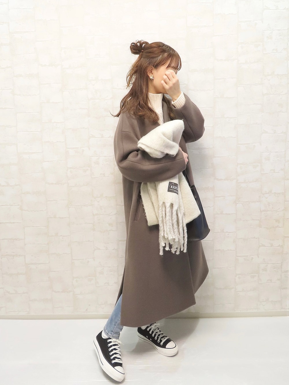 ベージュ系のニット/セーター、ブラウン系のノーカラーコート、ブルー系のデニムパンツを着用したレディースの秋コーディネートの2枚目の写真
