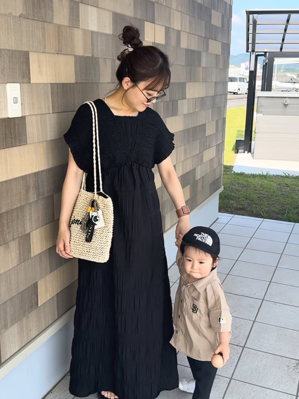 ブラック系のワンピース、ベージュ系のかごバッグ、ブラック系のサンダルを着用したレディースの夏コーディネートの4枚目の写真