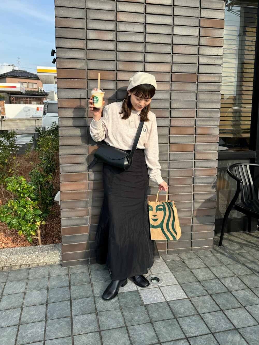 ベージュ系のポロシャツ、ブラック系のスカート、ブラック系のショルダーバッグを着用したレディースの秋コーディネートの5枚目の写真