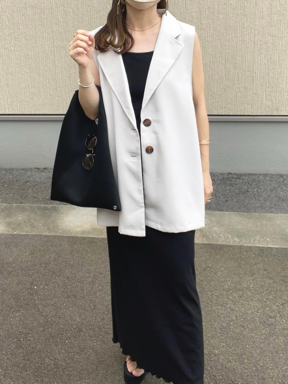 ベージュ系のベスト、ブラック系のワンピース、ブラック系のトートバッグを着用したレディースの夏コーディネートの3枚目の写真