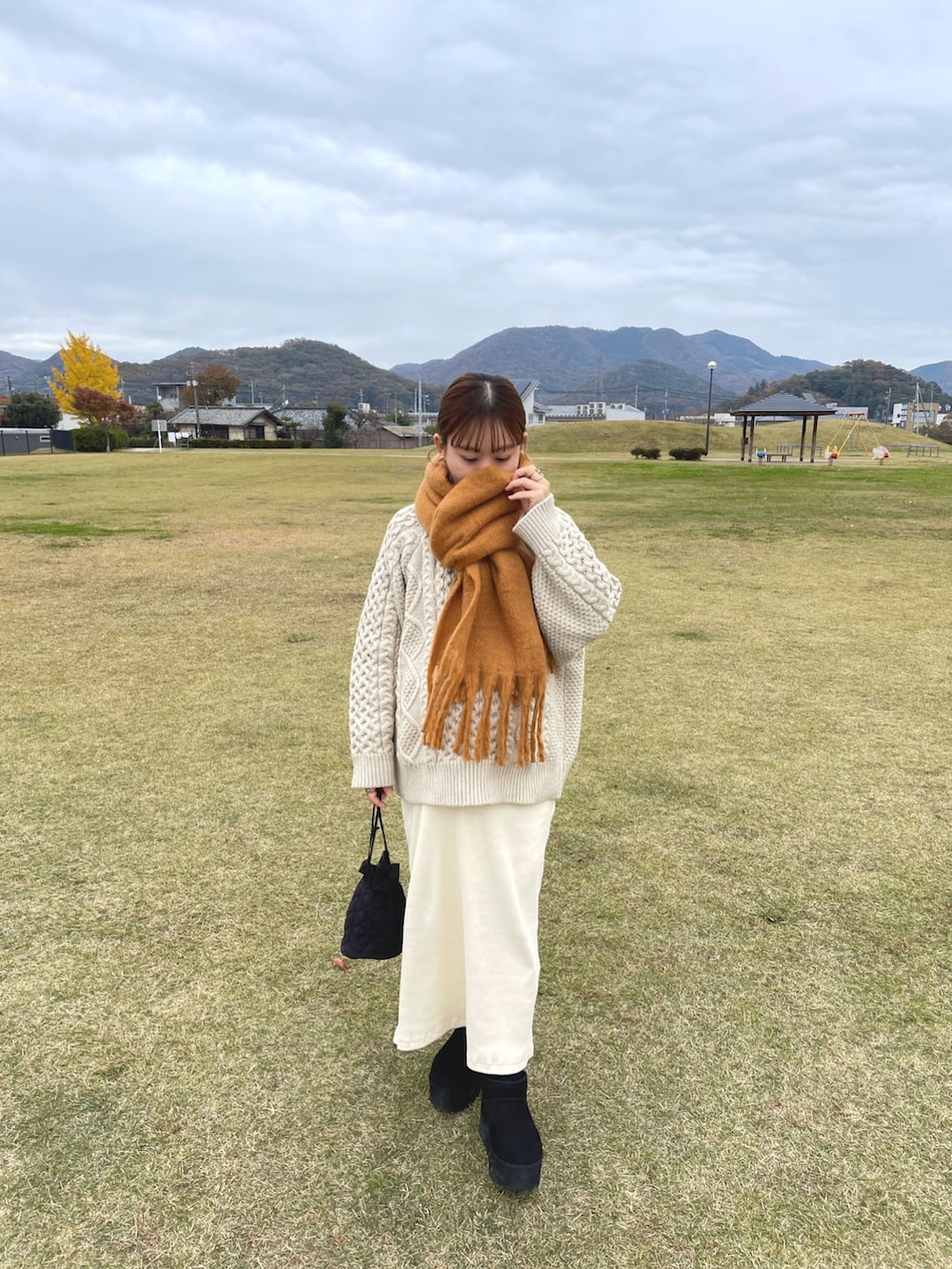 ホワイト系のニット/セーター、ホワイト系のスカート、ブラック系のブーツを着用したレディースの冬コーディネートの3枚目の写真