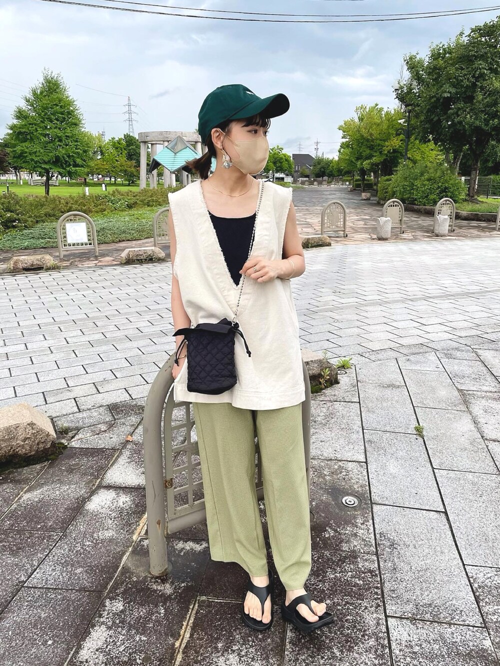 グリーン系のその他パンツ、ホワイト系のベスト、ブラック系のショルダーバッグを着用したレディースの夏コーディネートの4枚目の写真