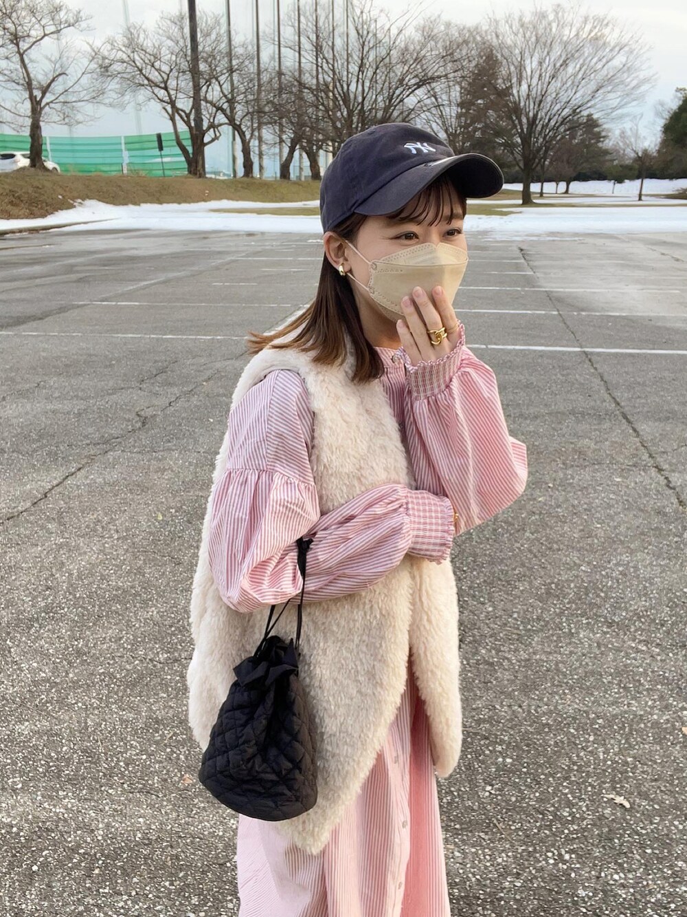 レッド系のワンピース、グレー系のベスト、ブラック系のショルダーバッグを着用したレディースの冬コーディネートの4枚目の写真