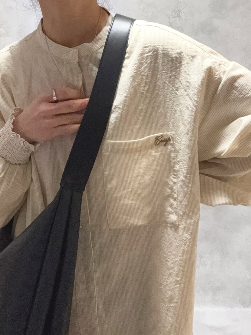 ベージュ系のシャツワンピース、ホワイト系のトップス、ブラック系のバッグを着用したレディースの冬コーディネートの5枚目の写真